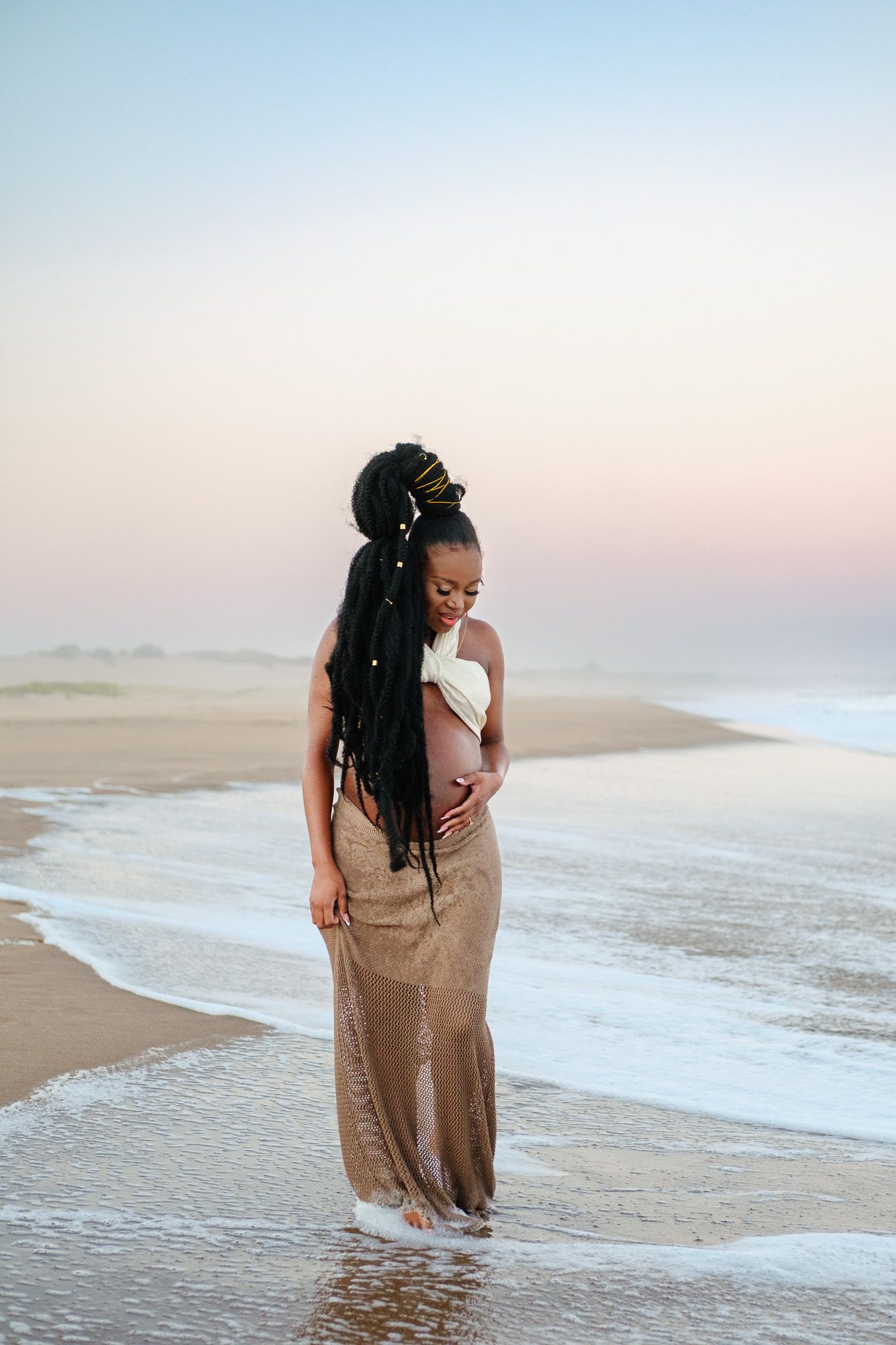 Pregnant woman standing in the ocean waves during a maternity photography session