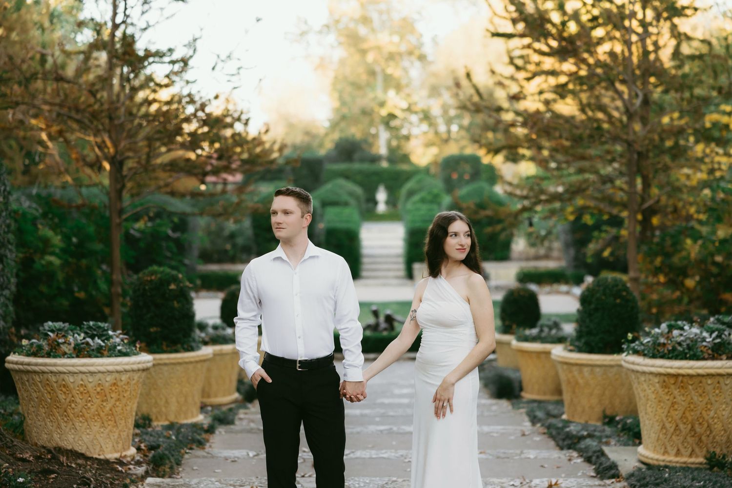 Bride and groom share romantic kiss at outdoor wedding ceremony with white floral arrangements and serene pond backdrop.