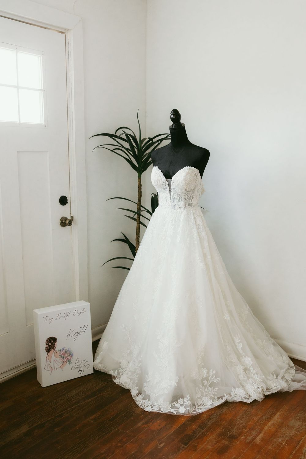 Elegant strapless lace A-line wedding gown displayed on mannequin in bright white bridal boutique room.