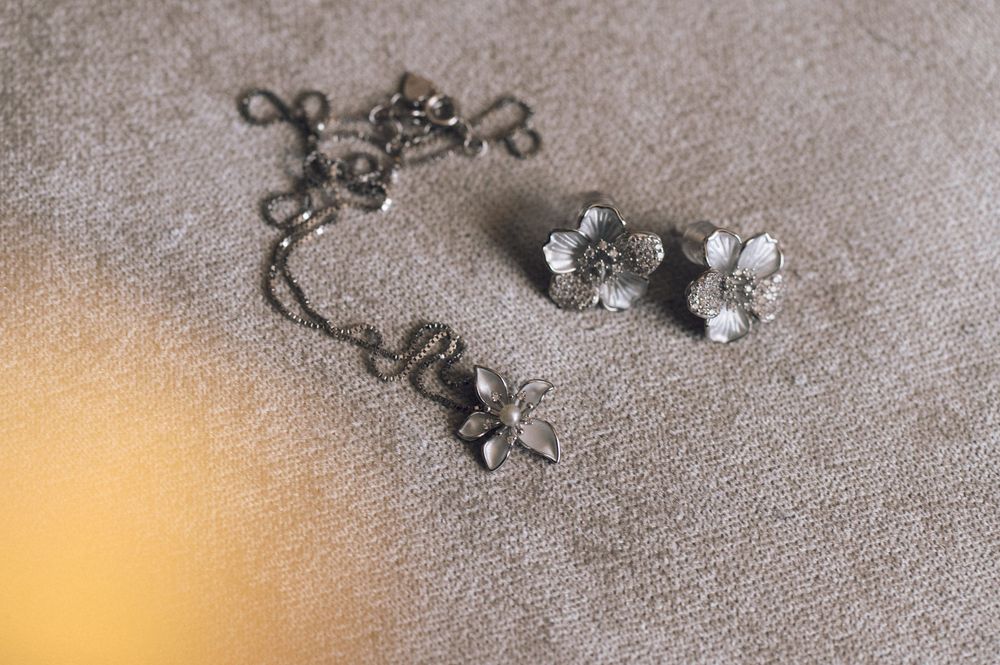 Vintage silver floral earrings and necklace set with crystal accents displayed on gray fabric.