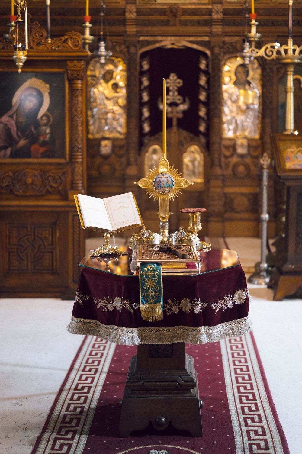Orthodox church altar with golden monstrance, open Bible, and ornate iconostasis in background.