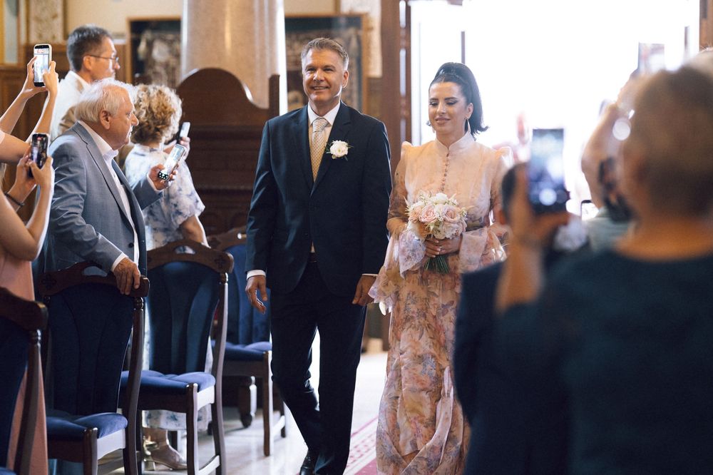 Bride and groom walking down the aisle at a wedding ceremony while guests watch and take photos.