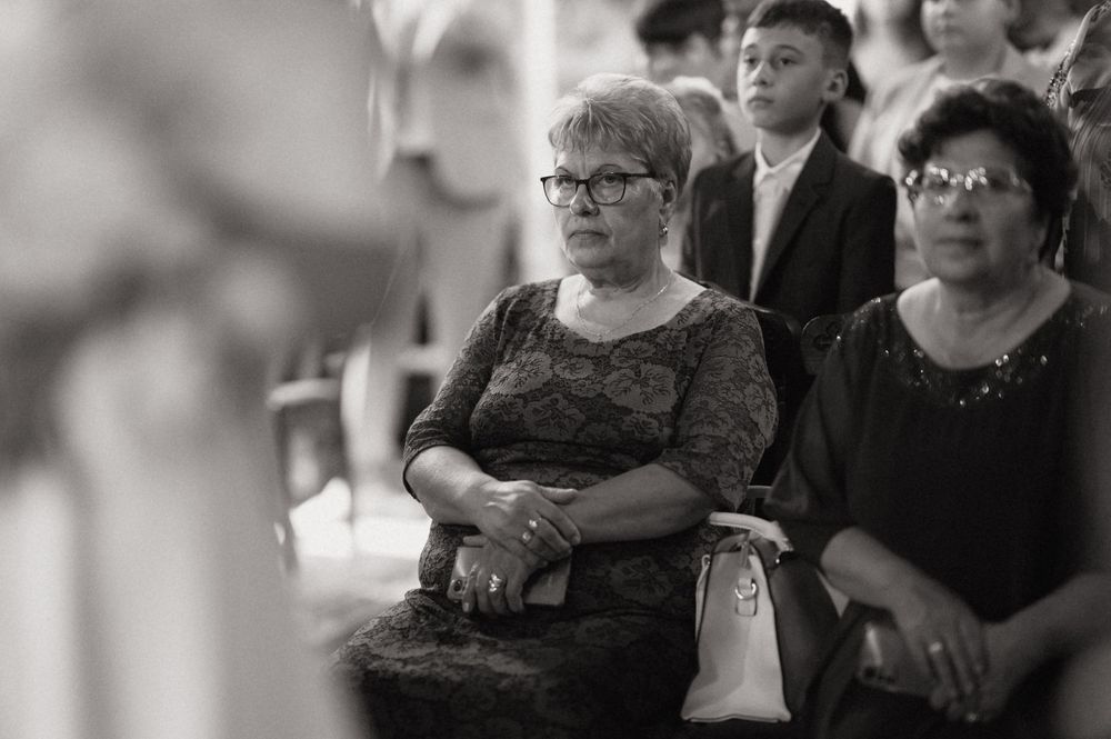 Black and white photo of two women seated at a wedding ceremony, with a young boy visible in the background.