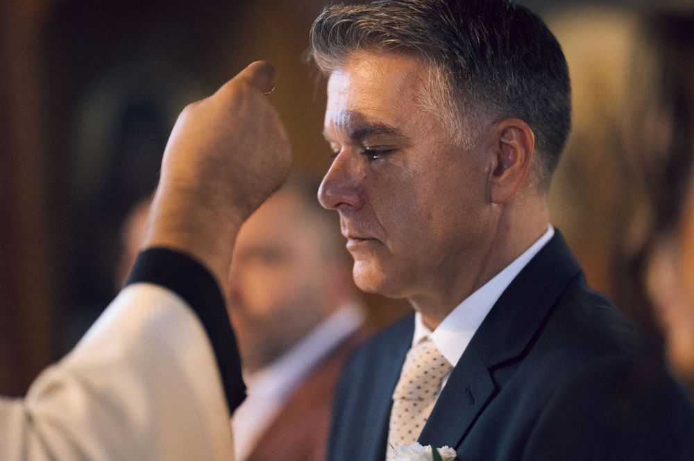 A priest anoints a man's forehead during a Catholic religious ceremony or sacrament.