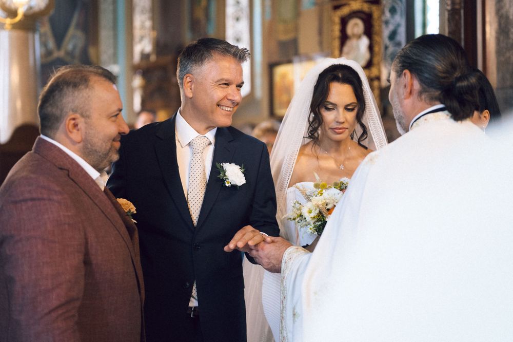 Bride and groom exchanging rings during a traditional church wedding ceremony with guests and priest present.