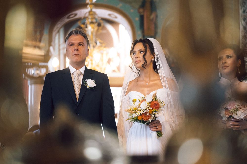 Bride holding bouquet stands with groom in elegant church wedding ceremony.