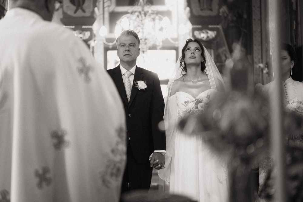 Black and white photo of a bride and groom holding hands during a church wedding ceremony.