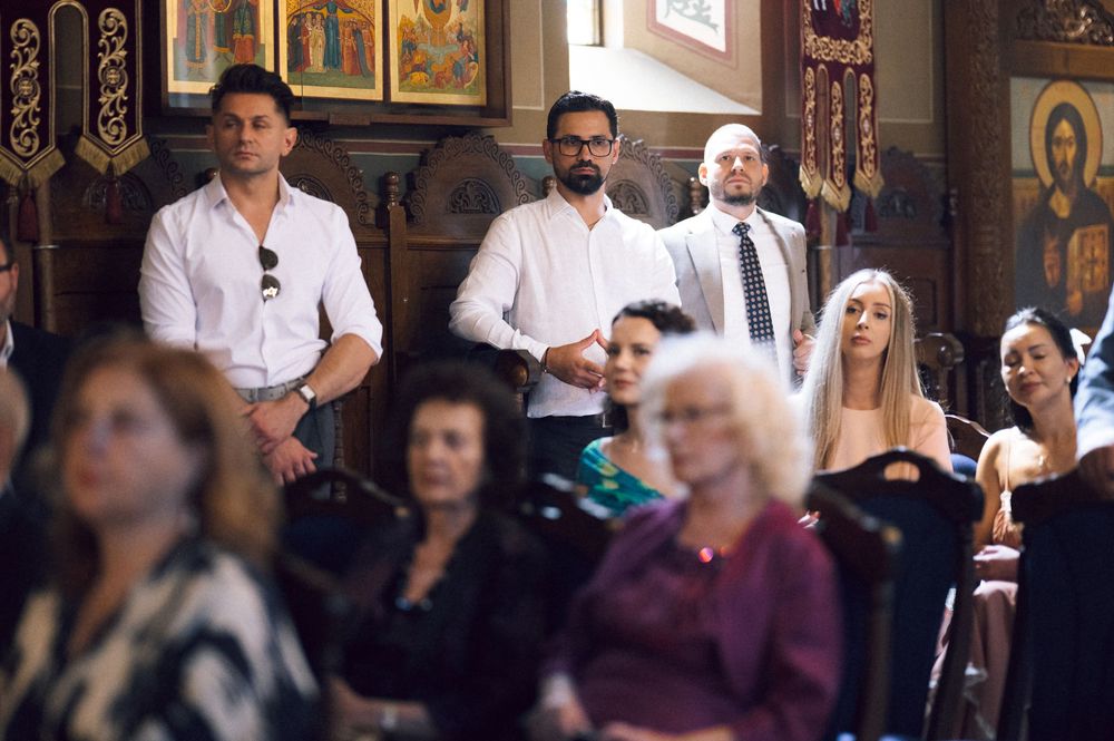 People standing and seated inside an ornate Orthodox church during a religious ceremony or service.