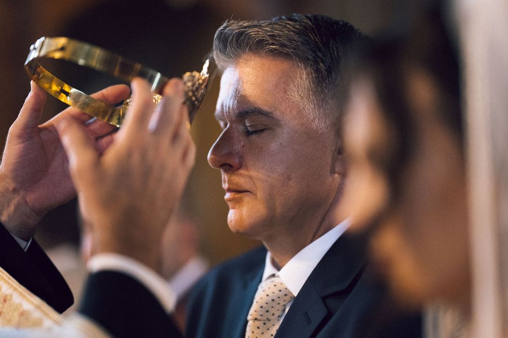 Man receiving holy anointing during a religious ceremony, eyes closed in reverence.