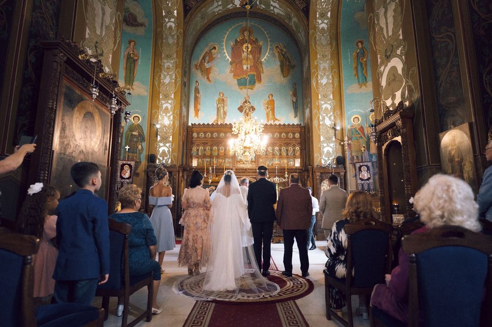 Bride and groom stand at the altar of an ornate Orthodox church during a traditional wedding ceremony.