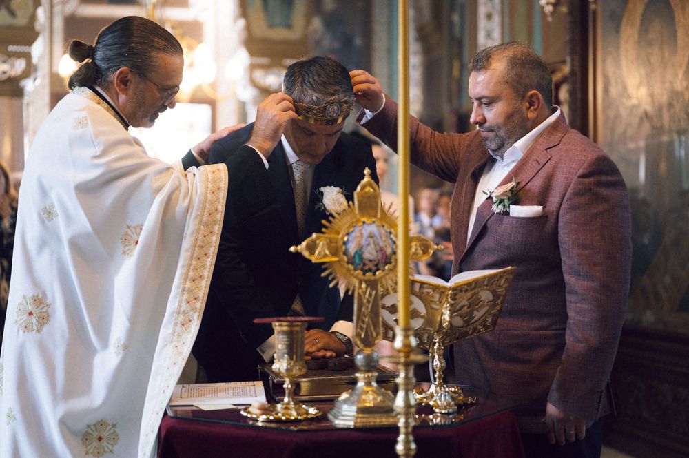 Priest performing a religious blessing ceremony with ornate golden altar pieces in a decorated church.
