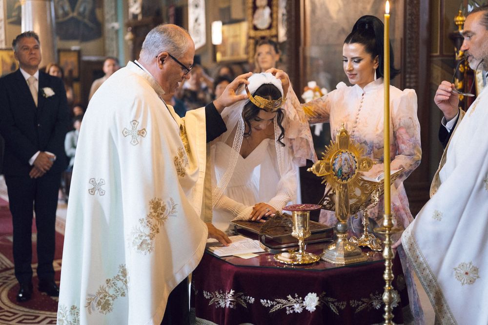 Priest officiating a religious ceremony with bride and guests at ornate church altar with golden decorations.
