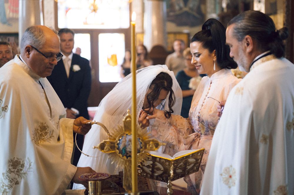Orthodox wedding ceremony with priest officiating as bride and groom exchange vows in ornate church.