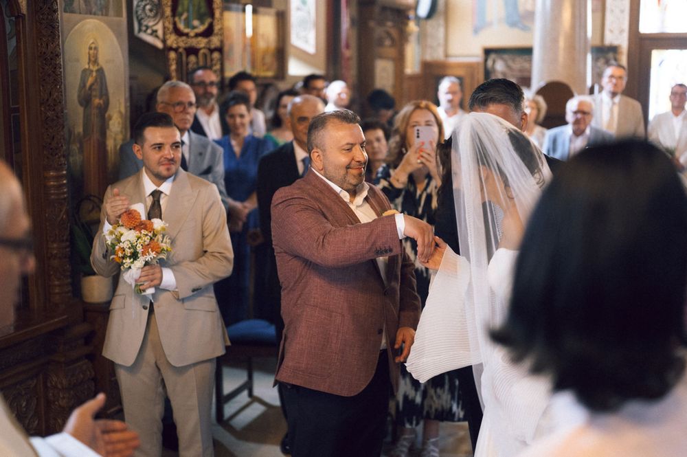 Father walking bride down the aisle in a decorated church during a traditional wedding ceremony.