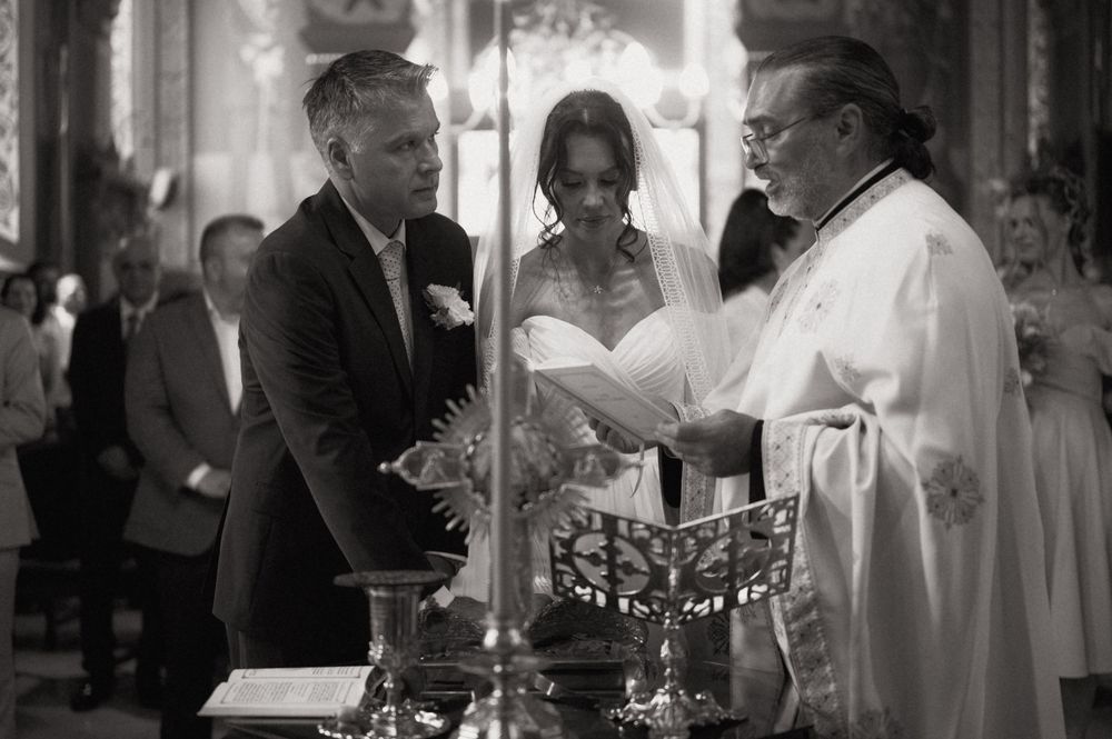 Black and white wedding ceremony photo with bride, groom, and officiant at church altar.