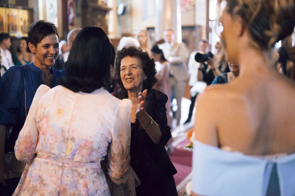 Women in elegant attire socializing at a wedding reception inside a decorated church venue.
