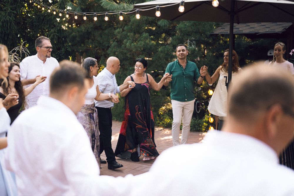 Guests dancing outdoors at an evening wedding reception under string lights in a garden setting.
