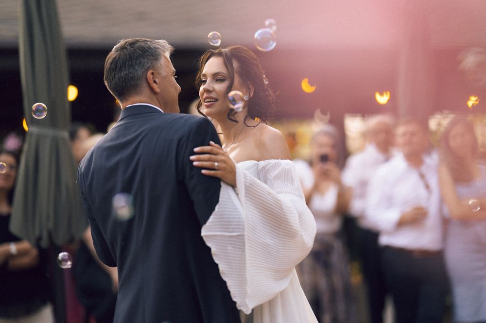 Bride and groom share first dance surrounded by floating bubbles at elegant wedding reception.