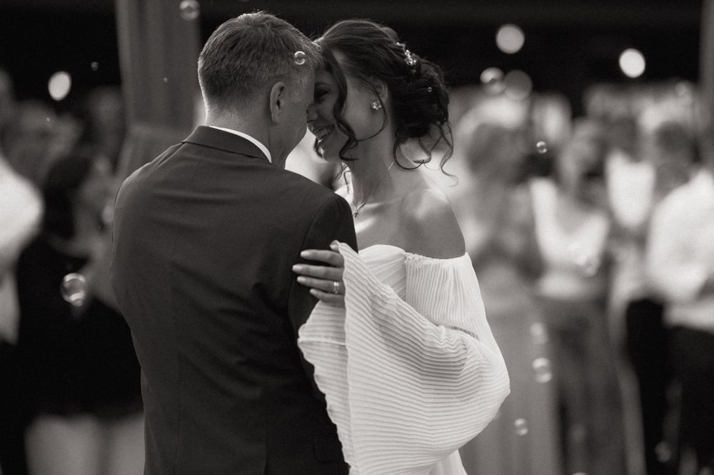 Black and white photo of a bride and groom sharing their first dance at a wedding reception.