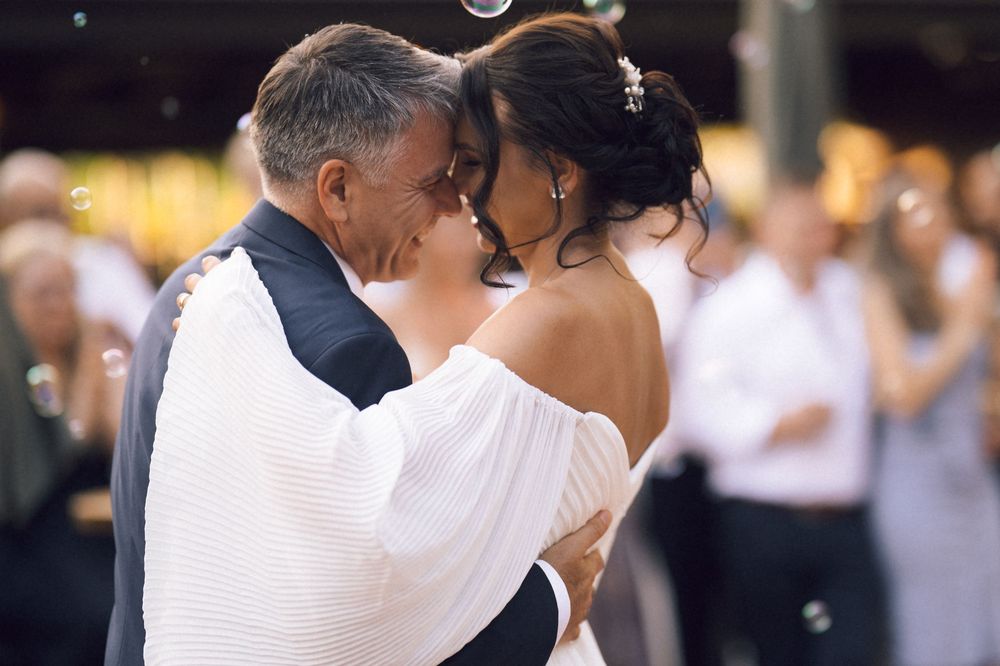 Couple sharing an intimate first dance at a wedding reception, surrounded by guests and floating bubbles.