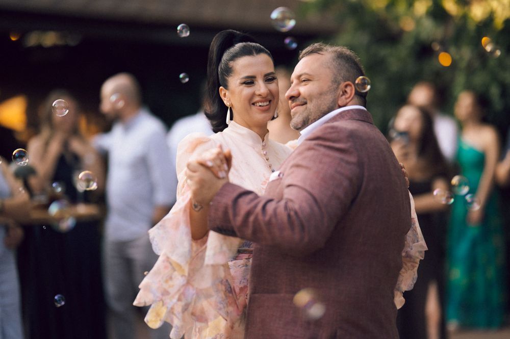 Couple shares first dance surrounded by bubbles at outdoor wedding reception.