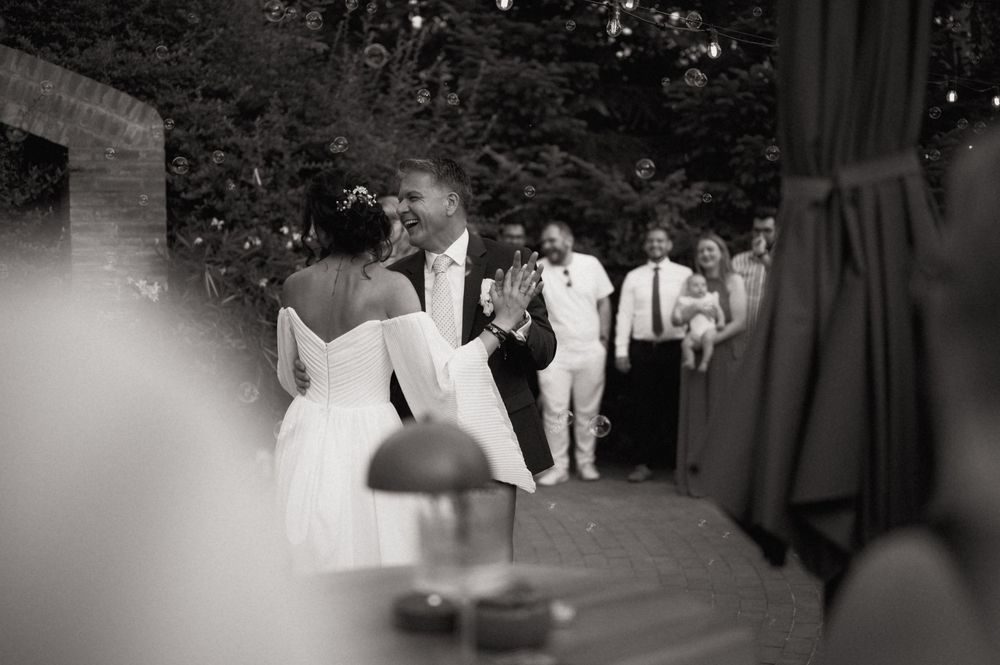 Black and white photo of a bride and groom sharing a dance at an outdoor wedding reception.