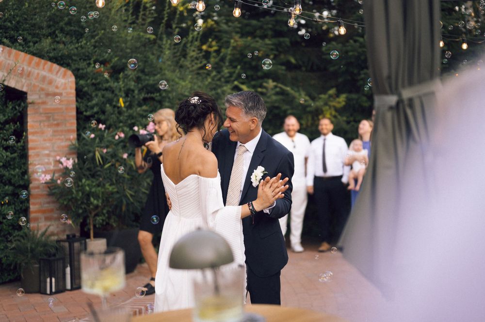 Bride and groom share a romantic first dance outdoors at an elegant garden wedding reception with guests watching.