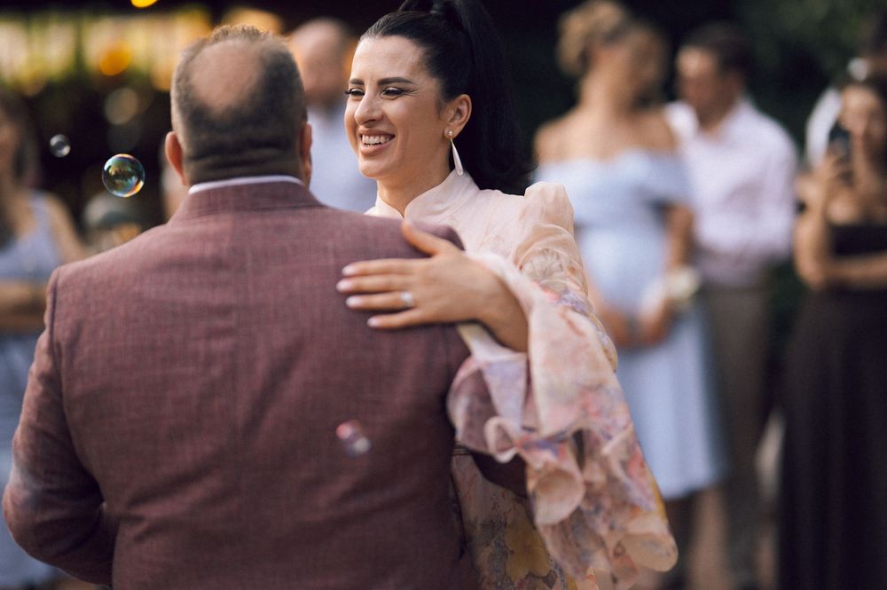 Couple sharing a romantic dance outdoors at a wedding celebration, woman smiling in elegant attire.