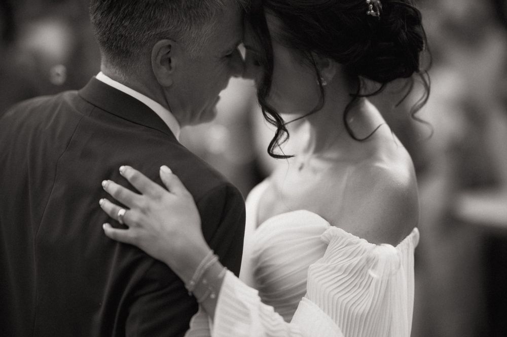 Black and white photo of a bride and groom sharing an intimate moment during their first dance at a wedding.