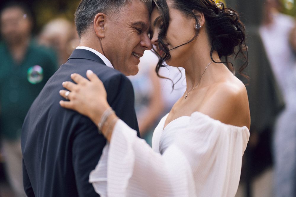 Bride and groom share an intimate moment during their first dance at an outdoor wedding ceremony.