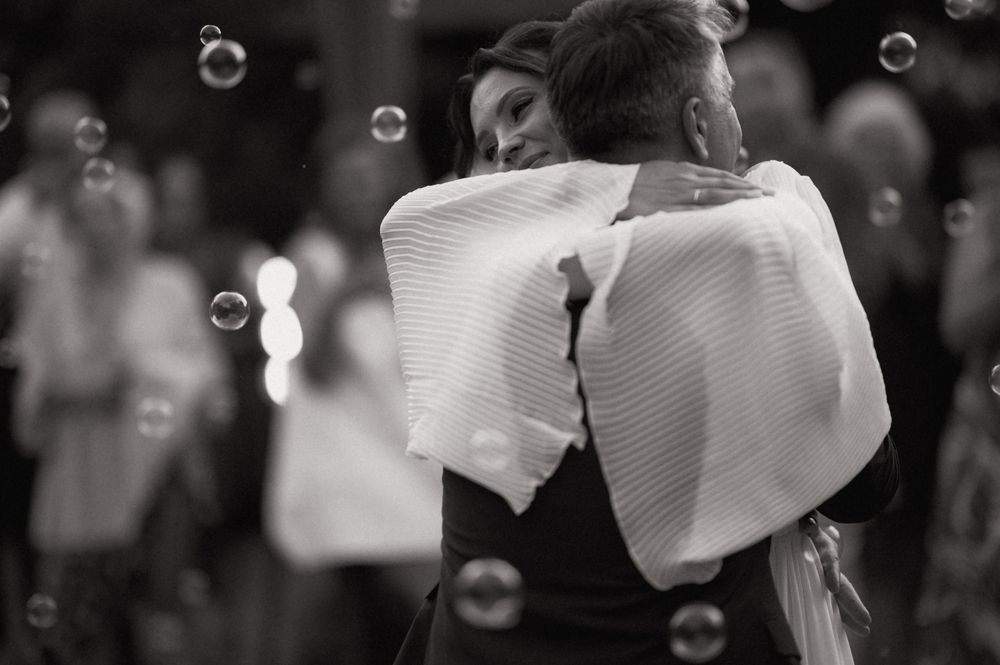 Black and white photo of a couple sharing a romantic dance embrace, surrounded by floating bubbles.