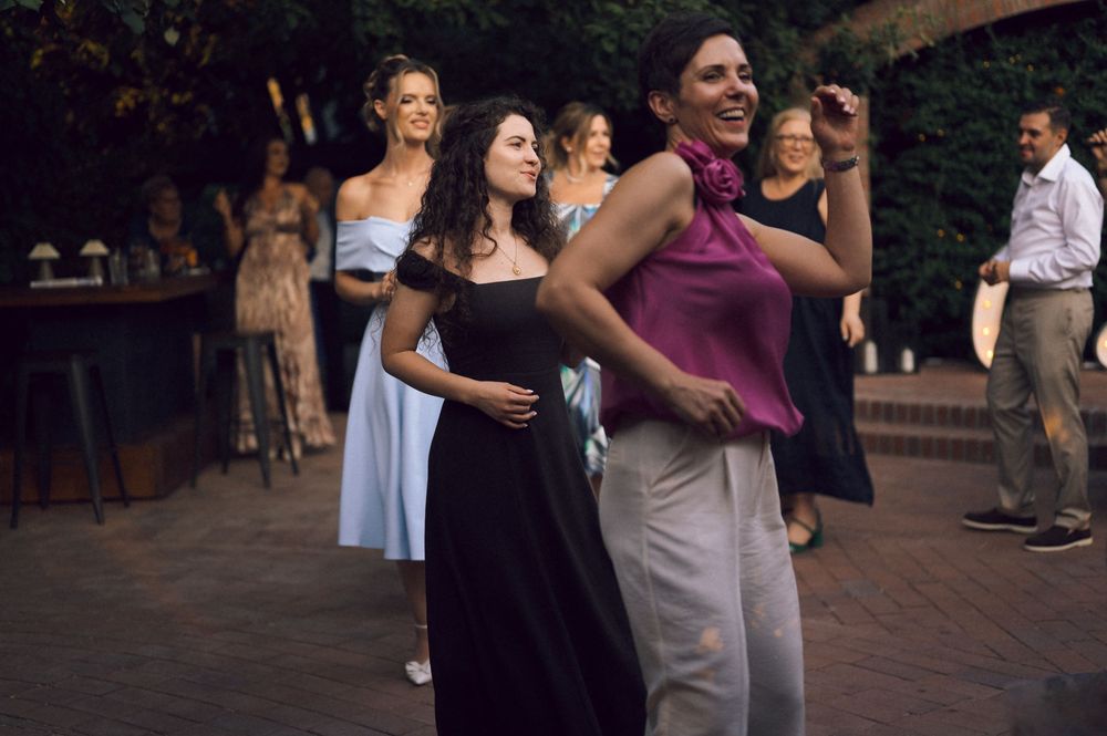Women dancing and socializing outdoors at an elegant evening party or wedding reception.