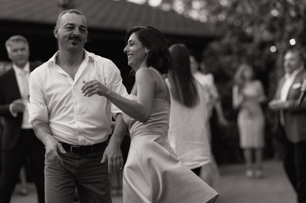 Couple dancing joyfully at a wedding reception in black and white photography.