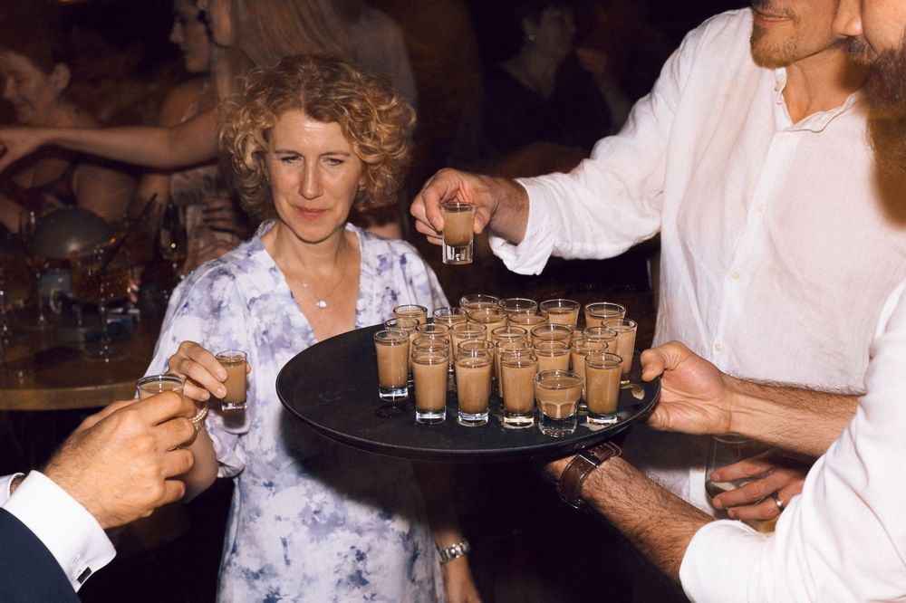 Guests taking espresso martini shots from a tray at an elegant party event.