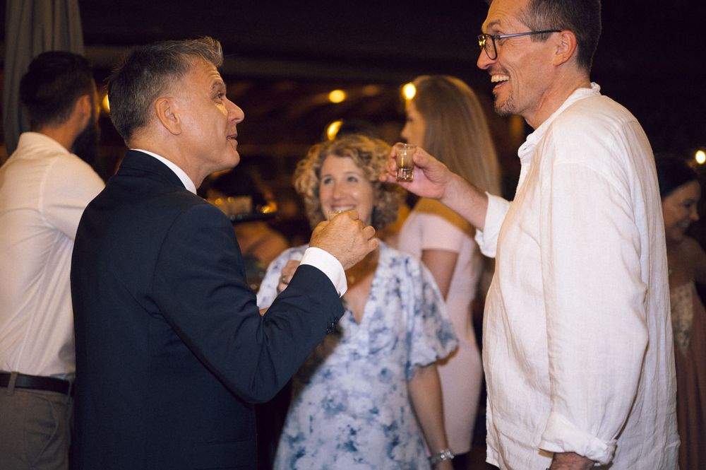 Three adults engaged in lively conversation at an elegant evening social gathering or wedding reception.