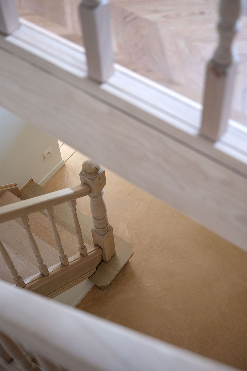 Overhead view of elegant white painted staircase with turned newel post and warm cork flooring below.