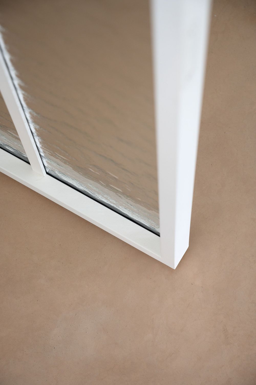 Close-up of a white PVC window frame corner resting on a beige floor, showing clean modern construction.