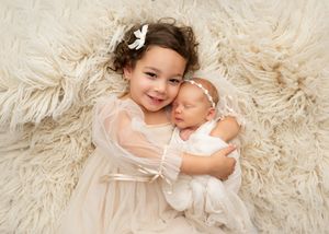 Older sibling cuddling a newborn baby during a family newborn photography session in New Jersey.
