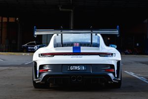 White Porsche 911 GT3 RS rear view with large wing in paddock.