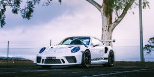 White Porsche 911 GT3 RS parked under cloudy sky near eucalyptus tree.