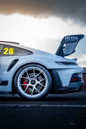 Close-up of white Porsche 911 GT3 number 26 showing rear wheel, red brake calipers and BOSS Hugo Boss wing spoiler.