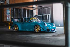Teal RWB Porsche 993 with gold wheels parked in multi-story car park garage entrance.