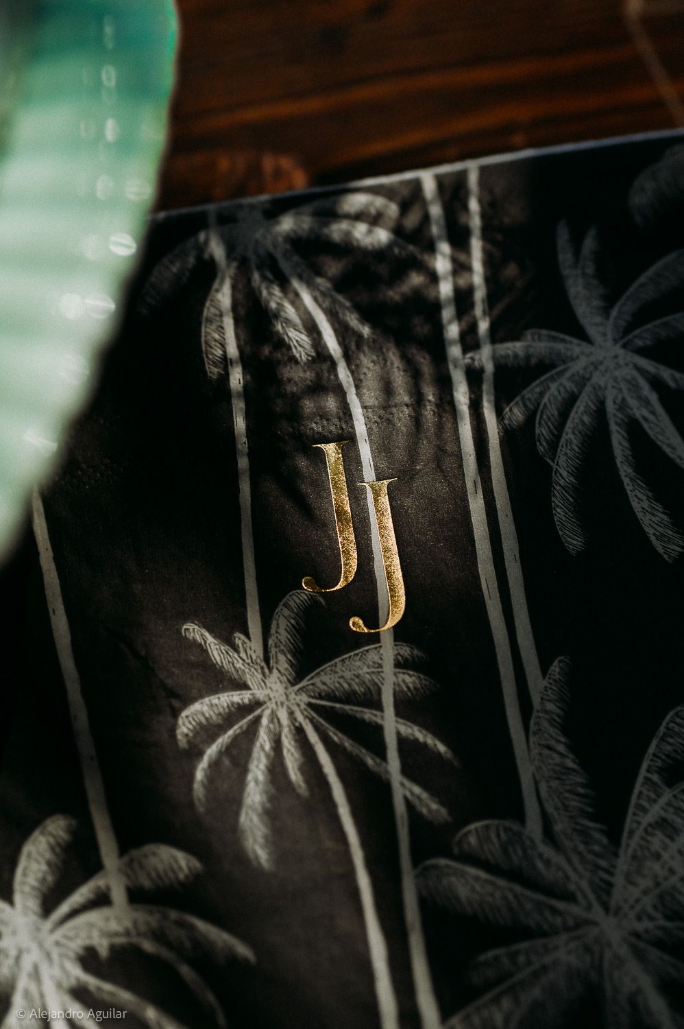 Dark fabric with gold JJ monogram initials and white palm tree pattern design.