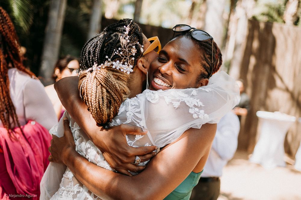 Two women share a warm embrace at an outdoor wedding celebration, smiling joyfully.