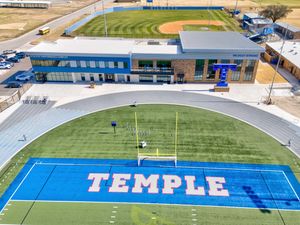 Aerial view of Temple Wildcats football field with blue turf end zone and modern athletic facility building.