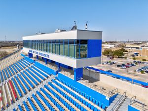 Press box and seating area at Wildcat Stadium featuring blue bleachers and glass-enclosed announcer booth.