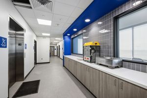 Modern stadium concourse area with concession counter, blue accent wall, and elevator access.