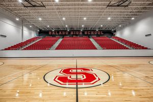Salado High School gymnasium with red bleachers, hardwood basketball court, and large red S logo at center court.