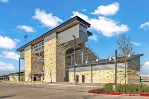 Modern commercial building with stone facade, large windows, and covered entrance under a blue sky.
