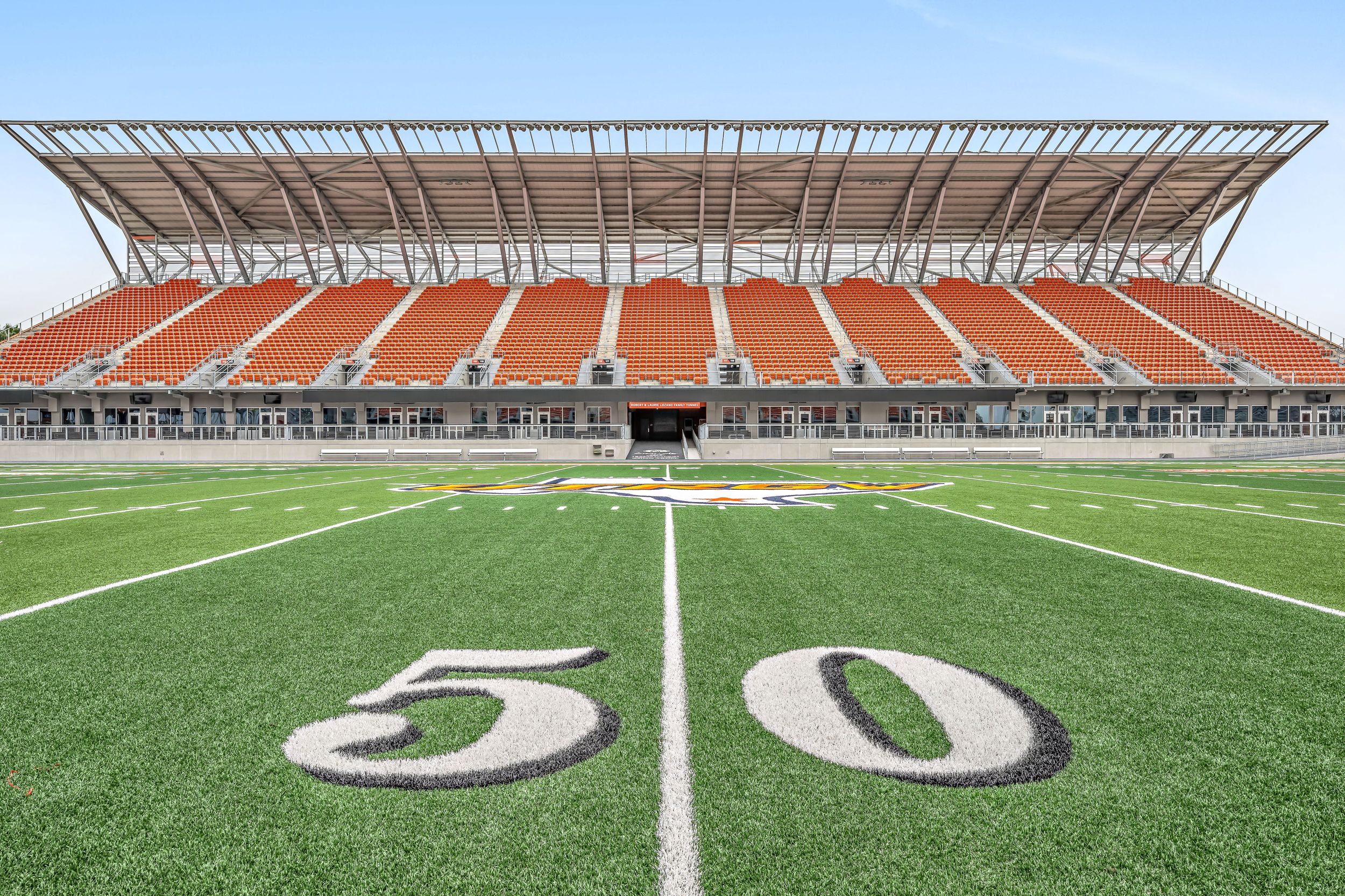 View from the 50-yard line of UTRGV Vaqueros football stadium with orange seating stands.